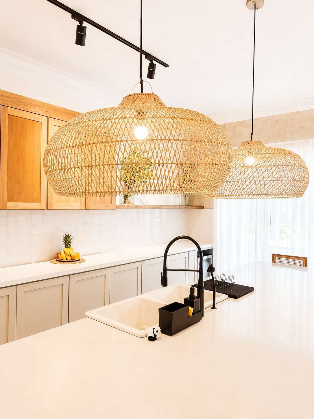 A kitchen with a white countertop, a black faucet, and a woven pendant light fixture.