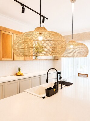 A modern kitchen with a white countertop, a black faucet, and two woven pendant lights. - Boho Retreat |Pool Cabana, Terrace Lounge, Rooftop (Sosúa)