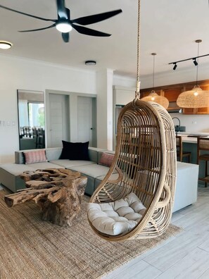 Ein modernes Wohnzimmer mit einem Hängestuhl, einem Couchtisch aus Holz und einer Couch.