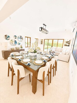 A spacious dining area with a large table set for six, surrounded by white chairs. - Sleeps up to 22 | Estate Pool 6bd Villa Corner Lot (Sosúa)