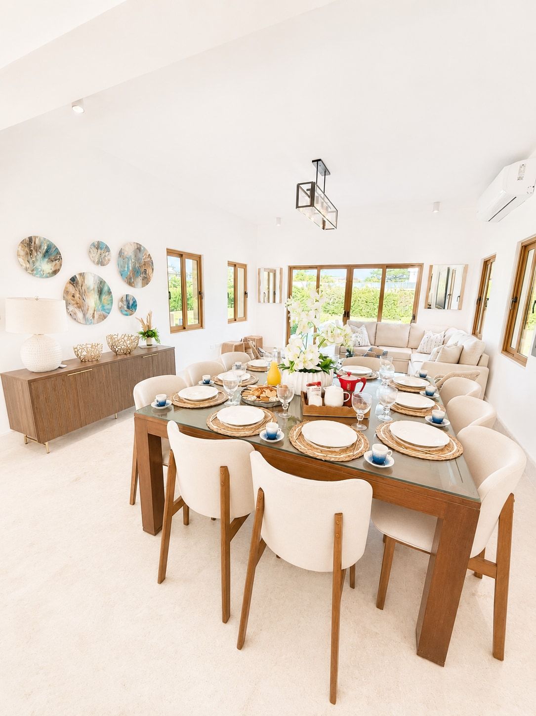 A spacious dining area with a round table set for six, surrounded by chairs.