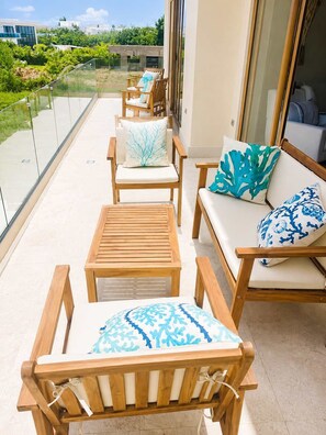 A balcony with wooden furniture, including chairs and a sofa, and a glass railing. - Sleeps up to 22 | Estate Pool 6bd Villa Corner Lot (Sosúa)