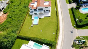 A modern multi-story building with a swimming pool and a well-maintained lawn. - Sleeps up to 22 | Estate Pool 6bd Villa Corner Lot (Sosúa)