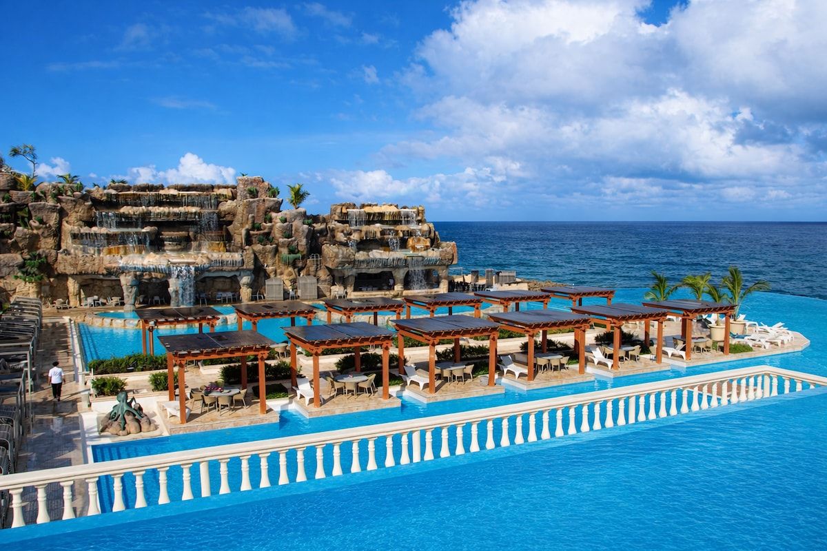 A resort pool with multiple levels and a view of the ocean.