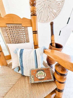 A wooden chair with a woven backrest, a cushion, and a decorative wooden box with a label. - Sleeps up to 22 | Estate Pool 6bd Villa Corner Lot (Sosúa)