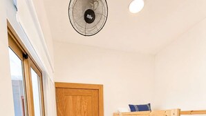 Une chambre à coucher avec un lit superposé en bois, une porte et un ventilateur de plafond.