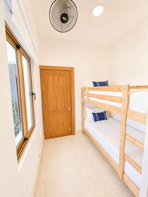 A bedroom with a wooden bunk bed, a door, and a ceiling fan. - Sleeps up to 22 | Estate Pool 6bd Villa Corner Lot (Sosúa)