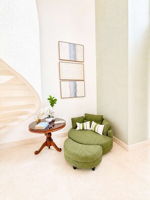 A room with a green upholstered sofa, a round wooden table with a plant, and three framed artworks on the wall. - Sleeps up to 22 | Estate Pool 6bd Villa Corner Lot (Sosúa)