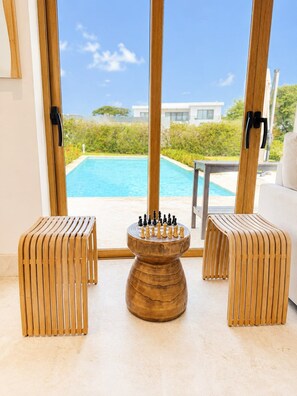 A chessboard set on a wooden table with a pool view. - Sleeps up to 22 | Estate Pool 6bd Villa Corner Lot (Sosúa)