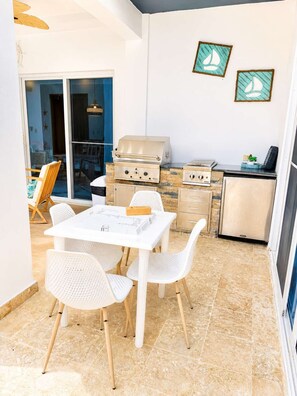 An outdoor patio with a white table and chairs, a grill, and a refrigerator. - Sleeps up to 16 | Family Villa w/ Bunk Room & Spa (Sosúa)