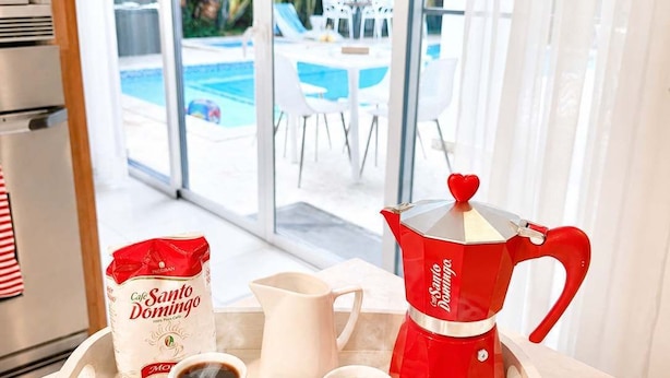 Un plateau avec une cafetière rouge, deux tasses de café et un sac de grains de café.
