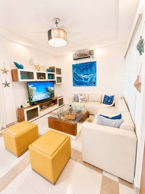 A modern living room with a flat-screen TV, a ceiling fan, and a painting on the wall. - Sleeps up to 16 | Family Villa w/ Bunk Room & Spa (Sosúa)