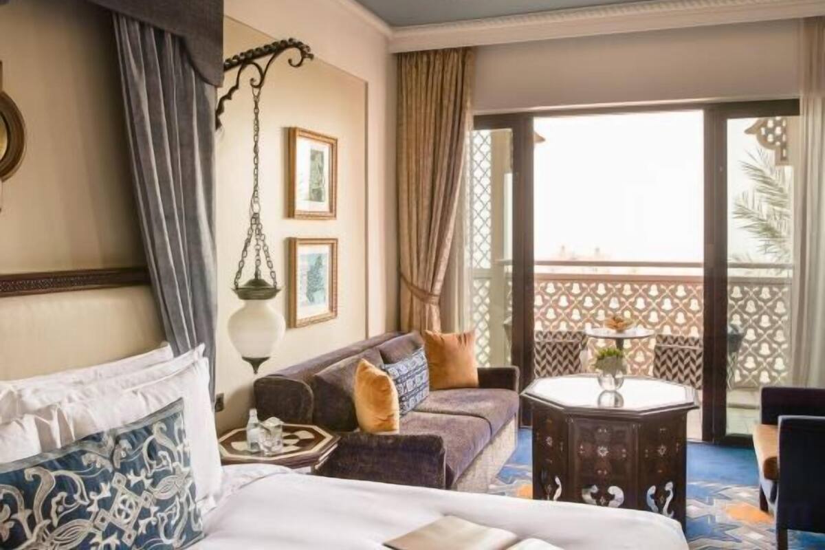 Una habitación de hotel con una cama, un sofá, una mesita y un balcón con vistas.