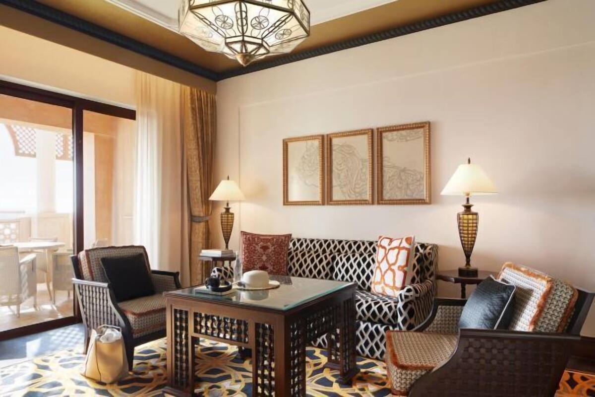 Habitación de hotel con sofá, sillas, mesa y candelabro.