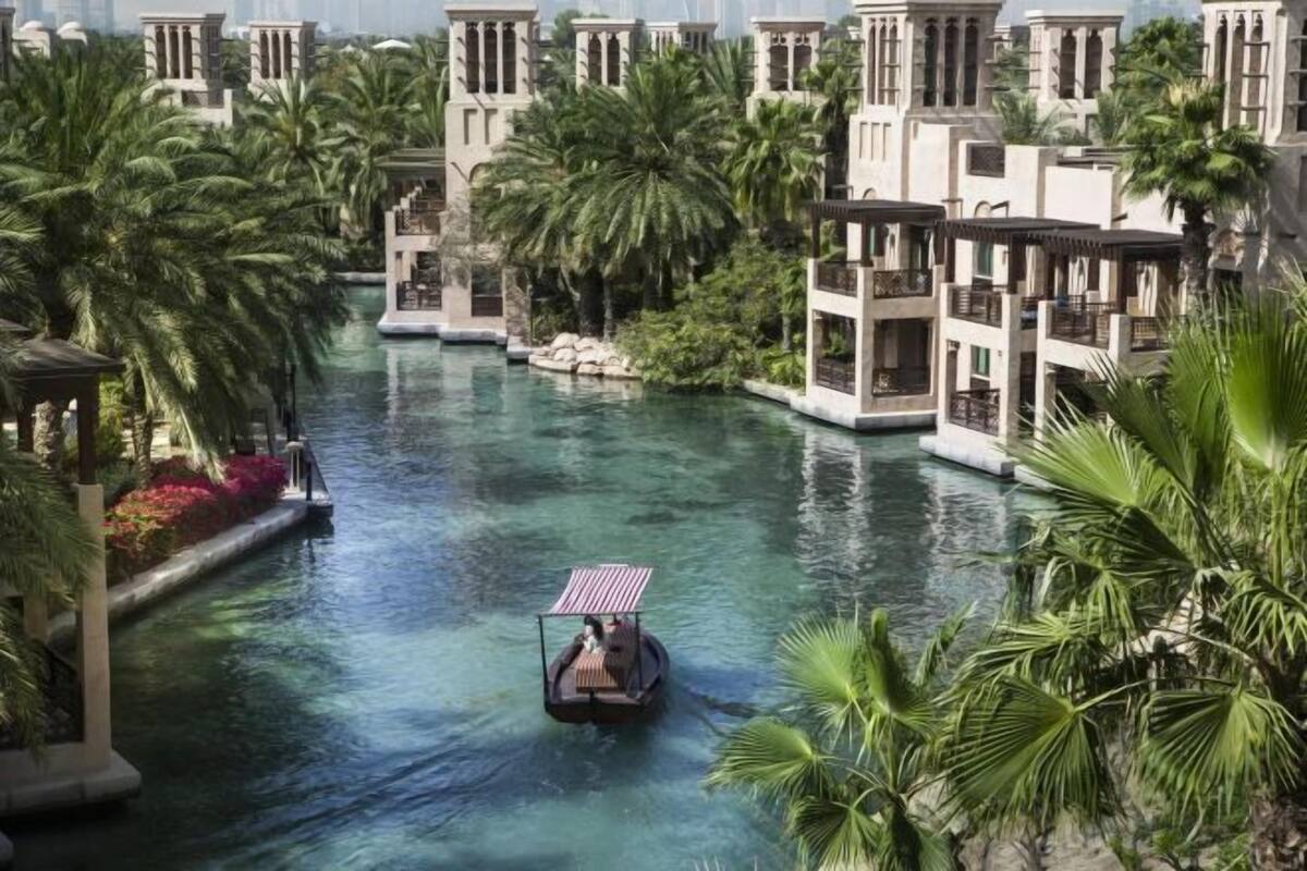 Un canal con un bote, rodeado de palmeras y edificios de arquitectura clásica.