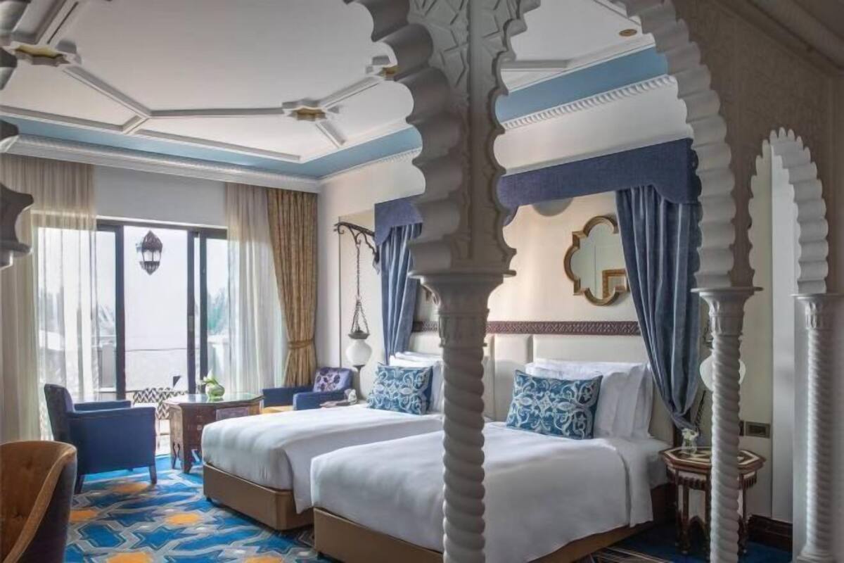Habitación de hotel con dos camas, un escritorio y una silla.
