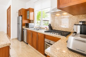 A modern kitchen with granite countertops, stainless steel appliances, and wooden cabinets. - Oceanfront Paradise | Cliffside Spa & Pool in SOV (Sosúa)