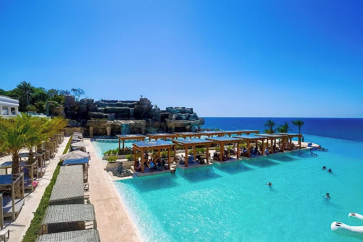 A resort with a large pool, outdoor seating, and a view of the ocean.