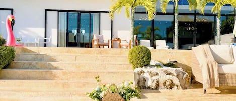 A modern outdoor area with a pool, seating, and palm trees.