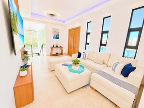 A modern living room with a sectional sofa, a coffee table, and a TV on a stand. - Sleeps up to 40 |8BR, Mini Golf & Largest Pool SOV (Sosúa)