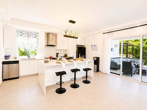 A modern kitchen with a central island, bar stools, and a view of the outdoors. - Sunset Villa | Bunk Room, Pool & Sleeps up to 11 (Sosúa)