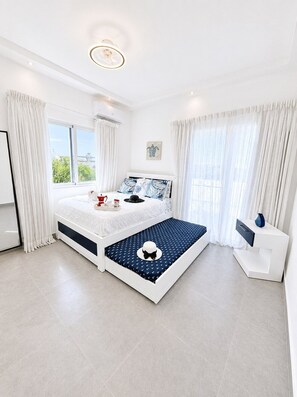 A modern bedroom with a large bed, a bedside table, a window with curtains, and a ceiling light. - Sunset Villa | Bunk Room, Pool & Sleeps up to 11 (Sosúa)