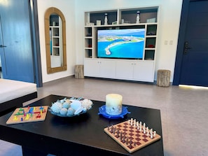 A living room with a TV, a chessboard, a board game, and a candle on a table. - Sunset Villa in Oceanfront Sosua Ocean Village (Sosúa)