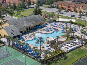 An aerial view of a resort with a central swimming pool, multiple lounge areas, and a tennis court. - Spacious 6BR Home | Pool | Near Disney, Universal (Kissimmee)