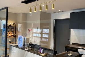 A reception desk with a computer, a glass partition, and a wall-mounted sign. - The Bayment Rasidence (Busan)