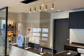 A reception desk with a computer, a glass partition, and a bulletin board. - The Bayment Rasidence (Busan)