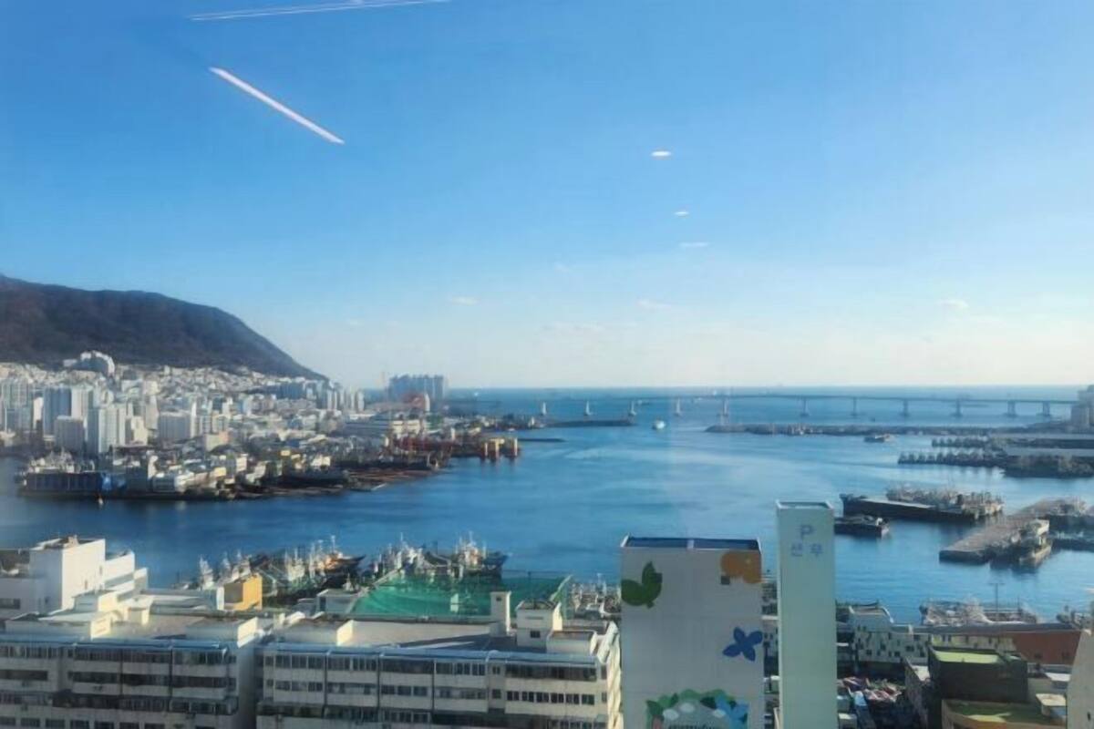 A coastal cityscape with a marina, buildings, and a bridge.