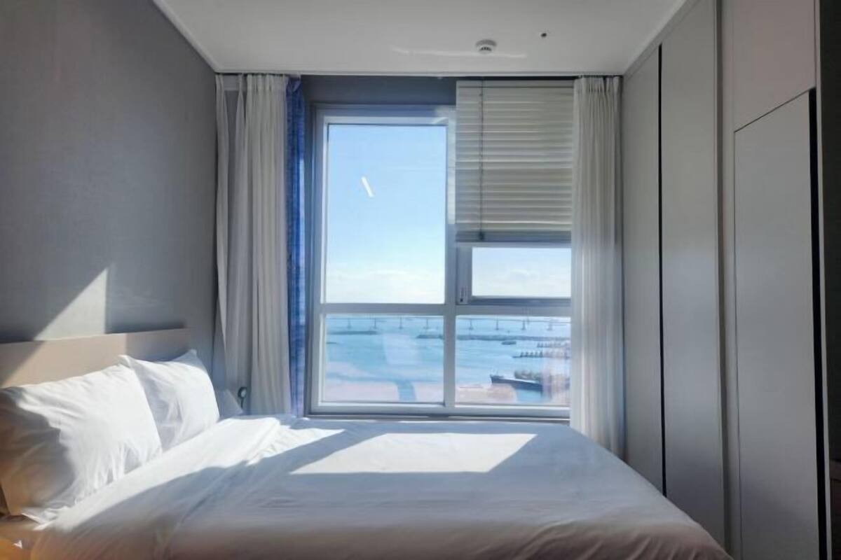 A hotel room with a large window, a bed, and a nightstand.