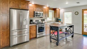 A modern kitchen with wooden cabinets, stainless steel appliances, and a cart.