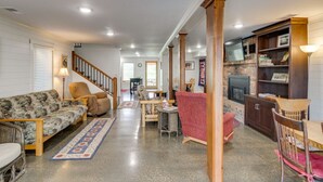 A spacious living room with a sofa, armchairs, a coffee table, and a fireplace.