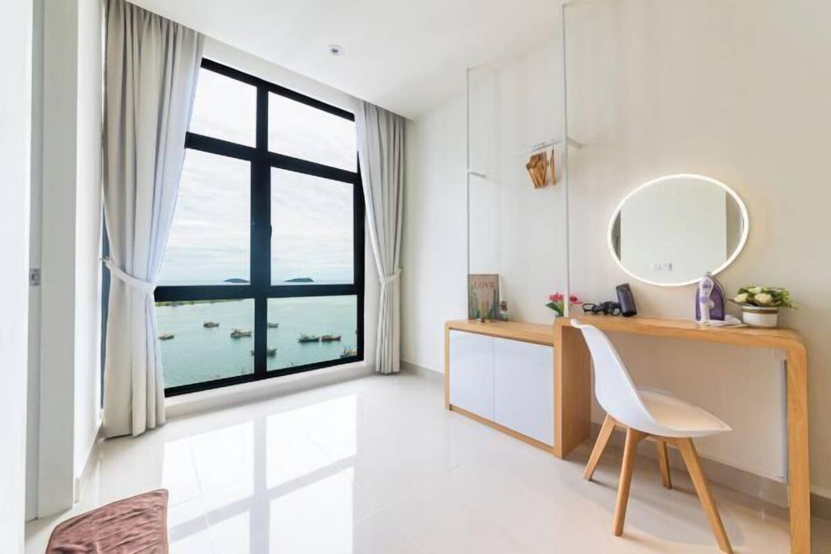 A modern room with a large window, a desk with a mirror, and a chair.