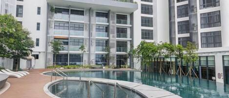 A modern building with a pool area, featuring a circular pool with a wooden deck and metal railings.