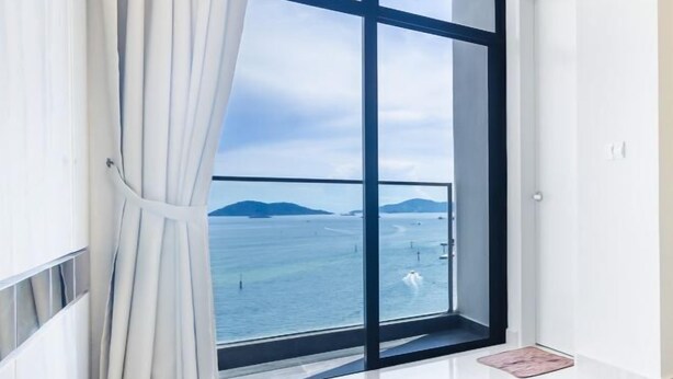Una habitación con un amplio ventanal que ofrece vistas al mar y montañas lejanas.