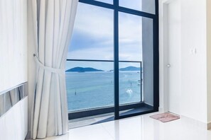 Ein Zimmer mit großem Fenster und Blick auf das Meer und ferne Berge.