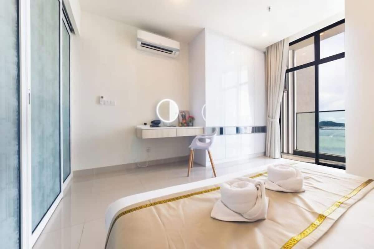A modern hotel room with a large bed, a vanity with a mirror, and a view of the outdoors.