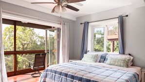 Un dormitorio con una cama grande, ventilador de techo y balcón con una silla.