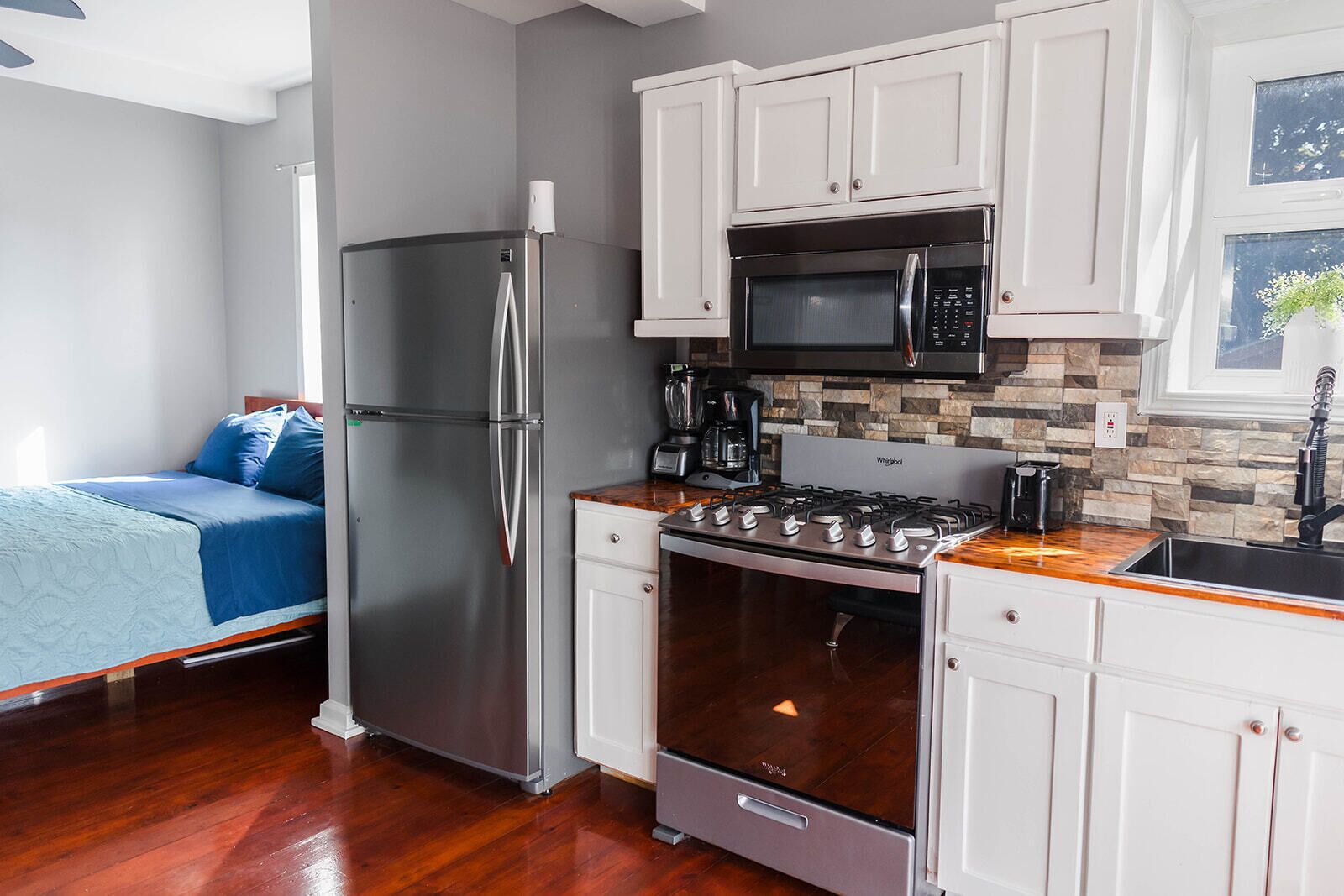 A compact kitchen with a refrigerator, microwave, stove, and sink.