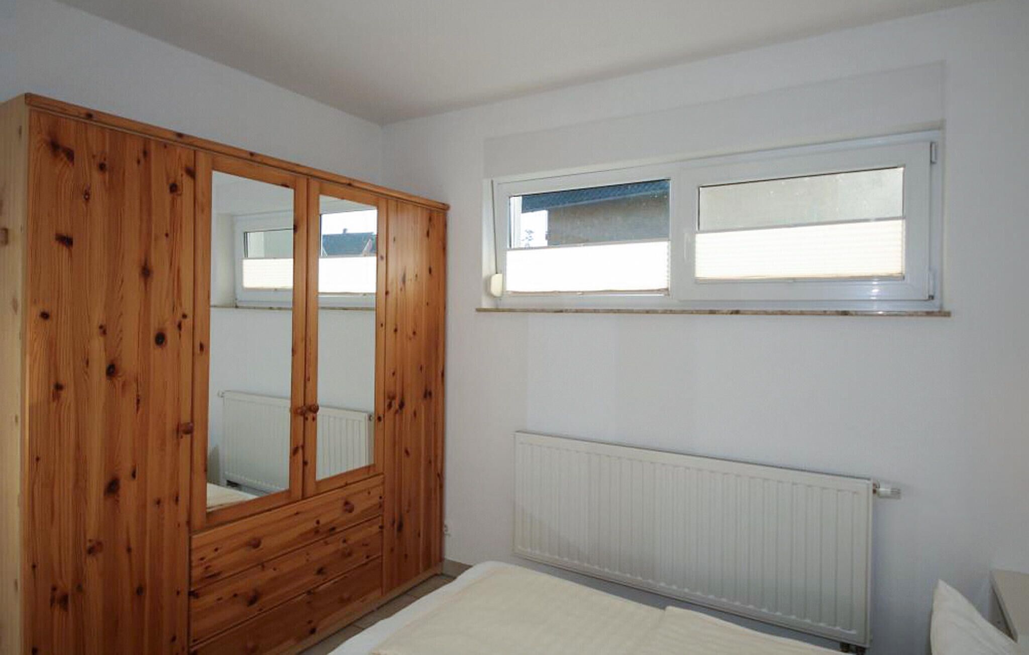 Un dormitorio con un armario de madera, una ventana y un radiador.