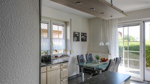 Een moderne keuken met een glazen eettafel, twee stoelen en een zwart aanrecht.