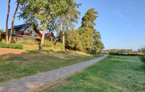 A paved path leading through a grassy area with trees and a building with a red roof. - 3 bedroom stunning apartment in Röbel (Röbel)