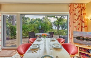 A dining area with a table set for six, chairs, a vase with flowers, and a painting on the wall. - 3 bedroom stunning apartment in Röbel (Röbel)