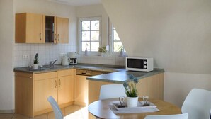 A modern kitchen with wooden cabinets, a built-in microwave, and a dining area with a table and chairs. - Awesome apartment in Röbel with lake view (Röbel)