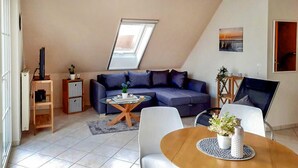 A modern living room with a sofa, coffee table, and a dining area with a table and chairs. - Awesome apartment in Röbel with lake view (Röbel)