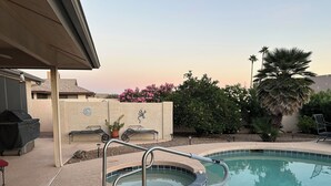 A pool with a built-in hot tub, surrounded by a patio area with a covered grill and outdoor seating. - Cozy 1-bedroom house in peaceful Sun City West with AC (Sun City West)