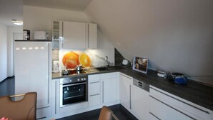 Une cuisine de taille réduite avec des meubles blancs, un four encastré et un plan de travail foncé.
