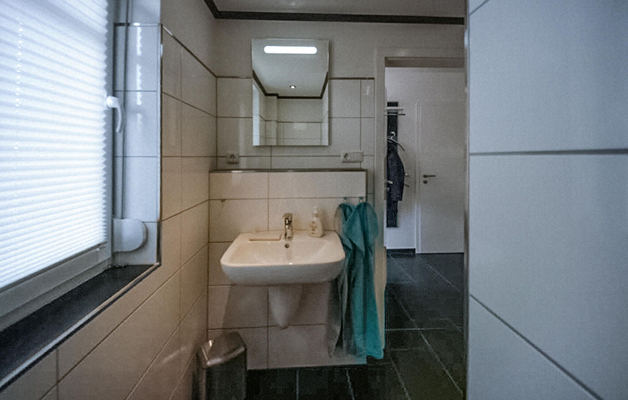 Ein Badezimmer mit Waschbecken, Spiegel und Handtuchhalter.
